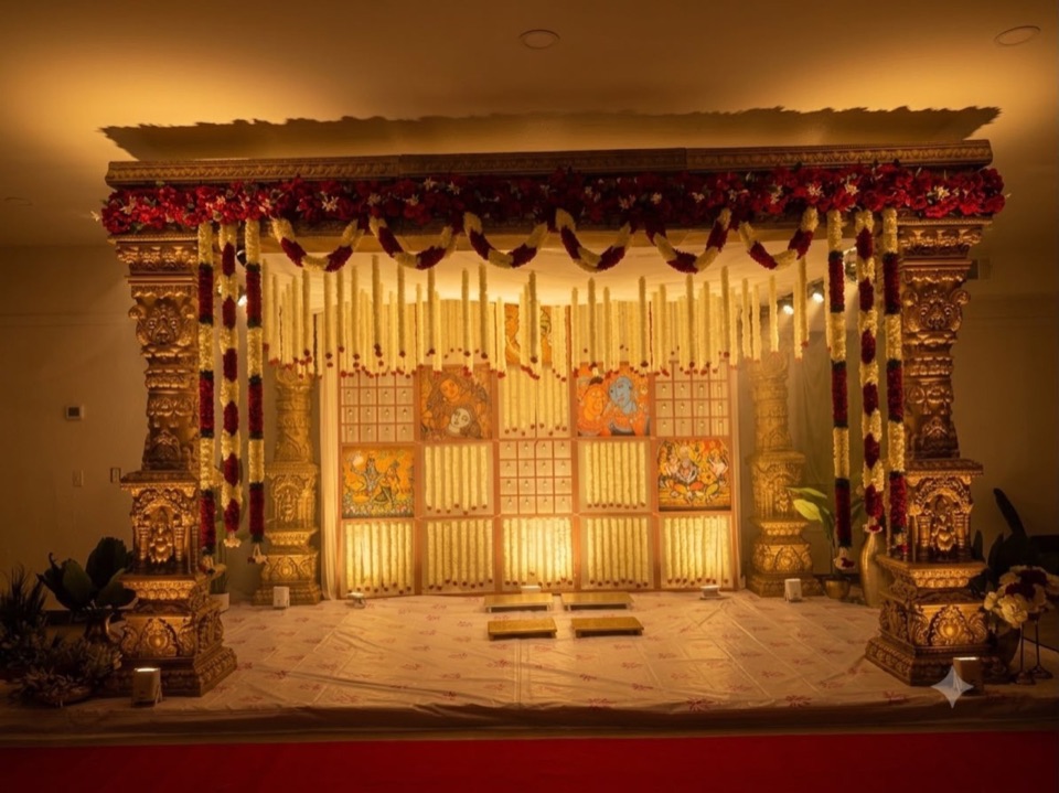 A temple inspired gold mandap glowing at night with jasmine strands and red garlands