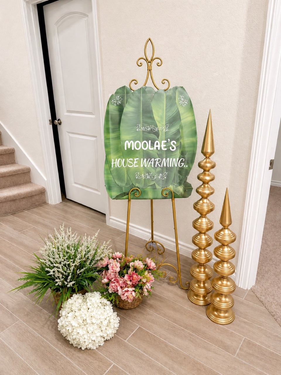 A housewarming welcome board on an easel, styled with florals at the entry