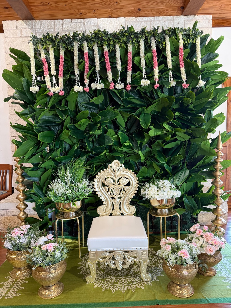 Banana leaf wall with jasmine garlands and a carved gold chair for a pelli kuthuru ceremony