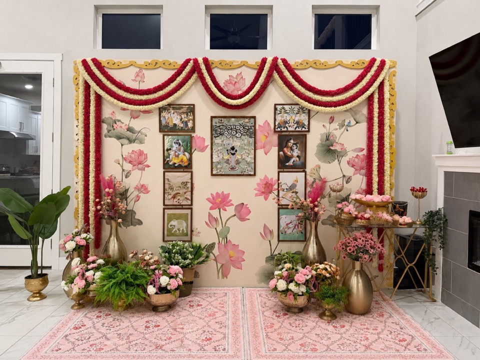 A lotus mural backdrop with framed traditional paintings and red and ivory garland swags