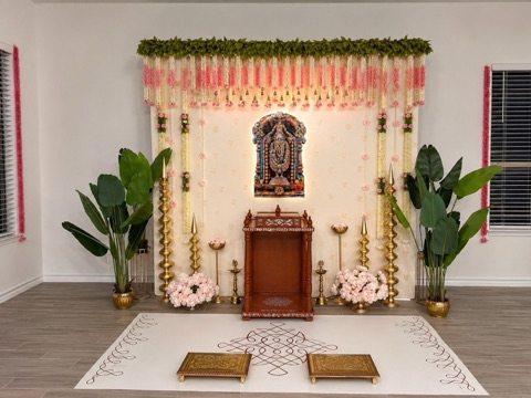 Home mandir styled with pink and ivory garlands and brass lamps