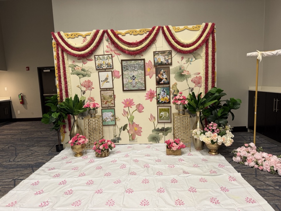 Lotus mural backdrop with framed traditional art and red and ivory garland swags